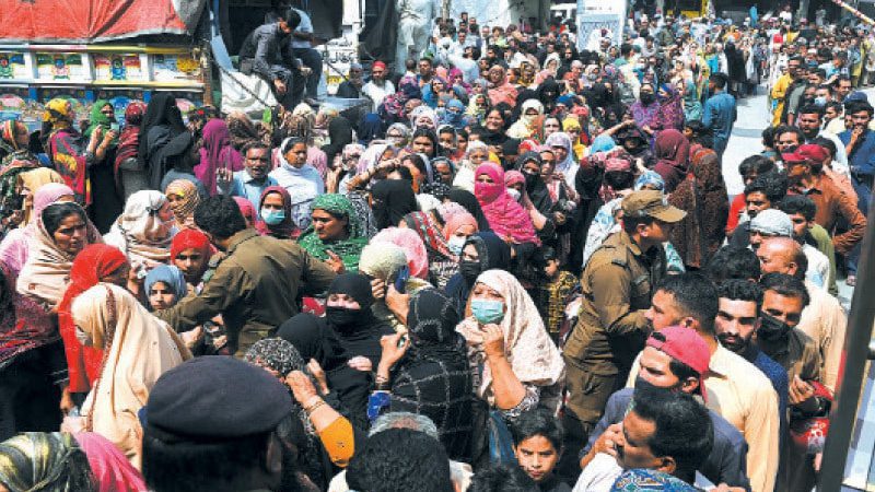 Police try to control the people gathered at a free flour distribution centre in Pakistan