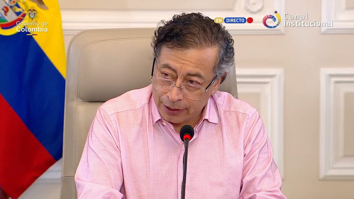 Colombian President Gustavo Petro sits at microphone in front of Colombian flag