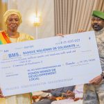 Malian woman and Assimi Goita hold up large check