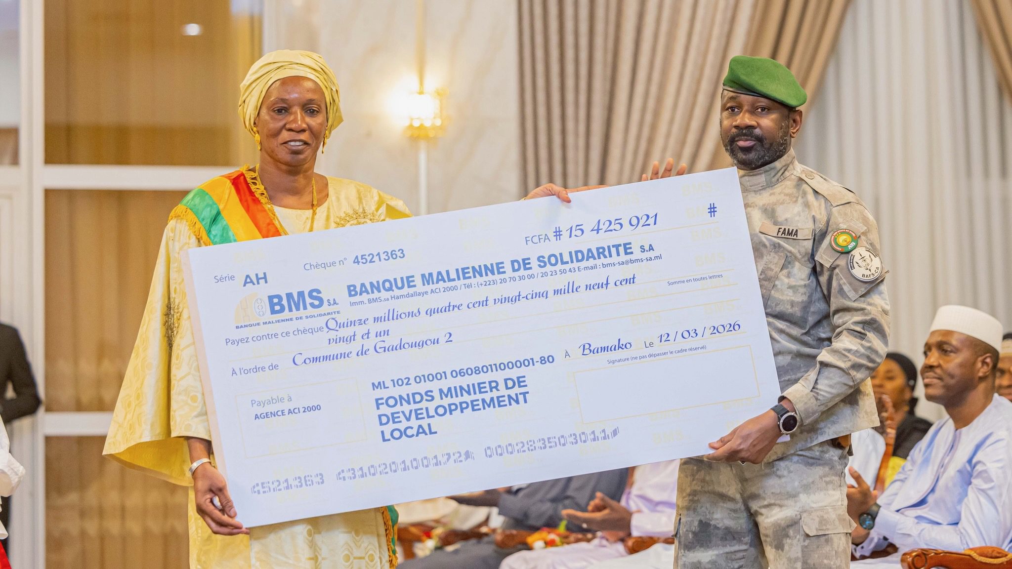 Malian woman and Assimi Goita hold up large check