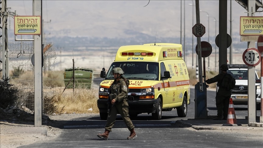 Israeli soldiers in front of yellow ambulance truck