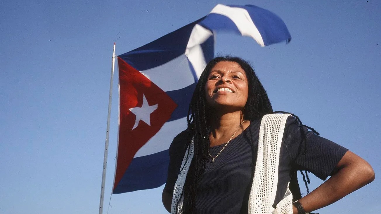 Assata Shakur in front of Cuban flag