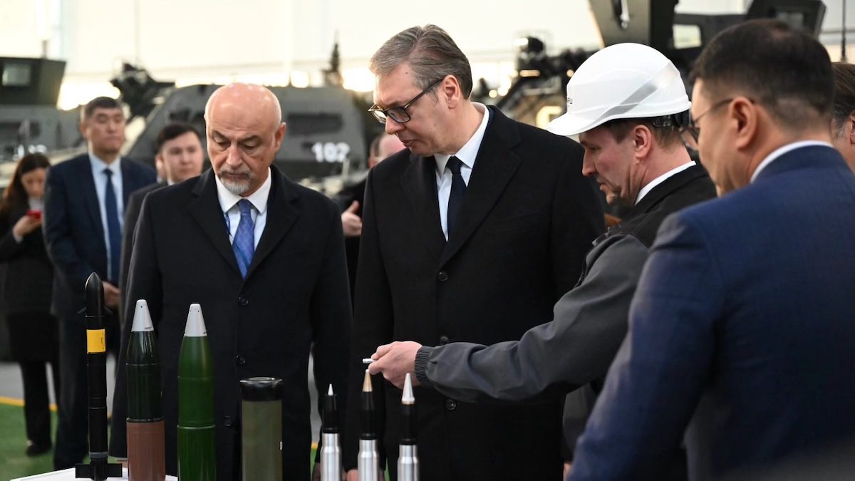 Serbian President Aleksandar Vučić looks at military products on table