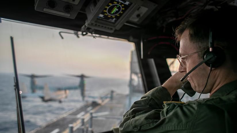 A naval officer aboard USS Tripoli oversees flight operations from the control tower as the amphibious assault ship sails in the Arabian Sea.