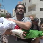 Father carries body of infant wrapped in Palestine flag