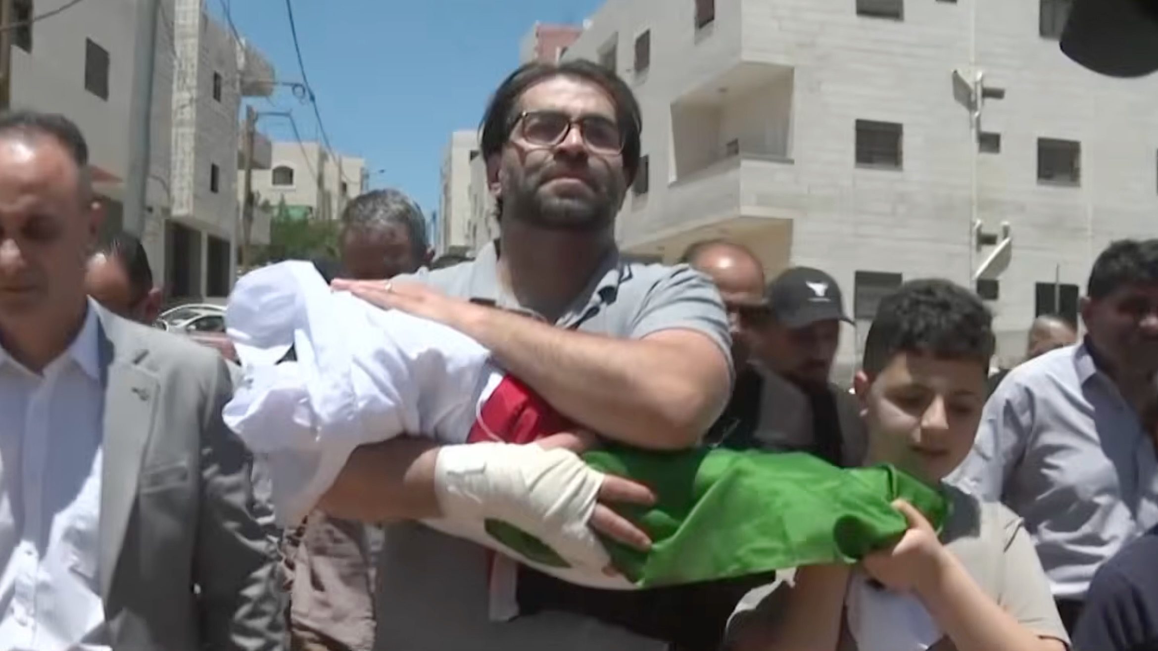 Father carries body of infant wrapped in Palestine flag
