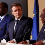 French President Emmanuel Macron, second right, listens to Ghana's President Nana Afuko Addo, right, with Senegal's President Macky Sall, and European Council President Charles Michel, left, standing at white podiums with their respective nations' flags behind them