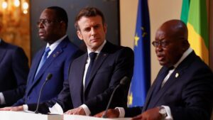 French President Emmanuel Macron, second right, listens to Ghana's President Nana Afuko Addo, right, with Senegal's President Macky Sall, and European Council President Charles Michel, left, standing at white podiums with their respective nations' flags behind them
