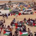 Activists wave Palestinian flags with vans and buses in the background