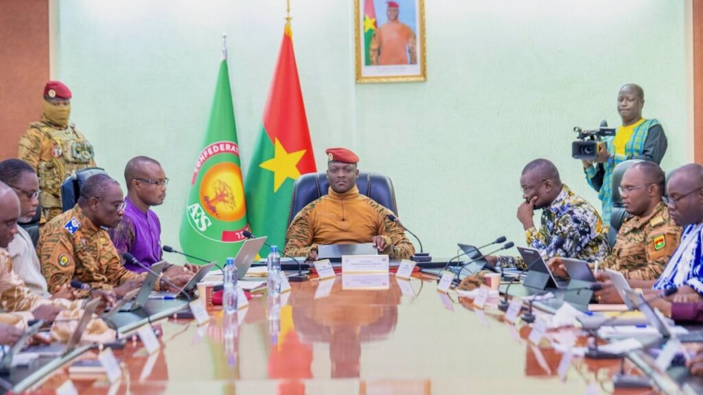 Burkinabé ministers sit around a table with AES and Burkina flags in background