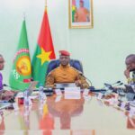 Burkinabé ministers sit around a table with AES and Burkina flags in background