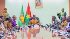 Burkinabé ministers sit around a table with AES and Burkina flags in background