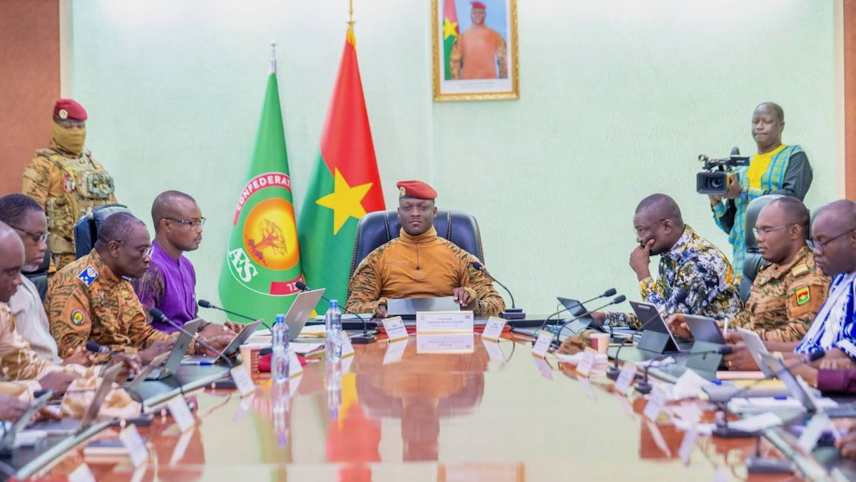 Burkinabé ministers sit around a table with AES and Burkina flags in background