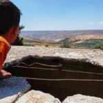 Syrian boy looks at a hole left by an Israeli shell