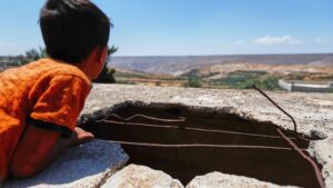 Syrian boy looks at a hole left by an Israeli shell
