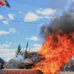 Tire on fire as man waves Kenyan flag