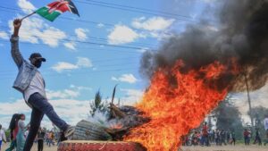 Man waves Kenyan flag near burning tire