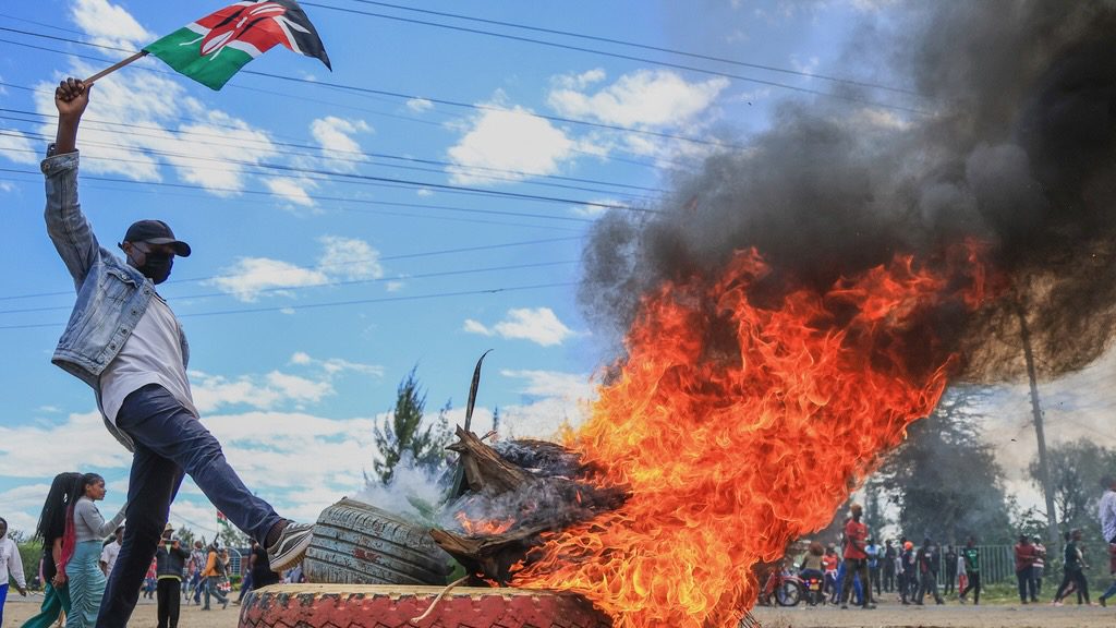 Man waves Kenyan flag near burning tire