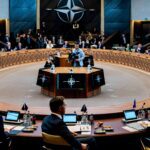 NATO defense ministers sit around a table