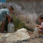 Displaced Palestinian children refill water containers
