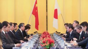 China and Japan - BT News Chinese and Japanese foreign ministers sit across a table from each other with their respective flags in the background