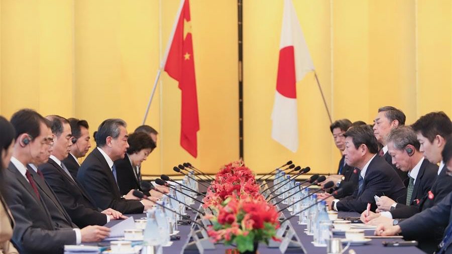 China and Japan - BT News Chinese and Japanese foreign ministers sit across a table from each other with their respective flags in the background