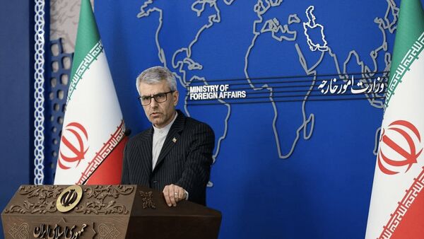 Esmail Baghaei at podium in front of blue background and flanked by Iranian flags