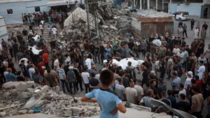 Gaza destruction - BT News Child looks out at a crowd moving bodies in bags amidst rubble