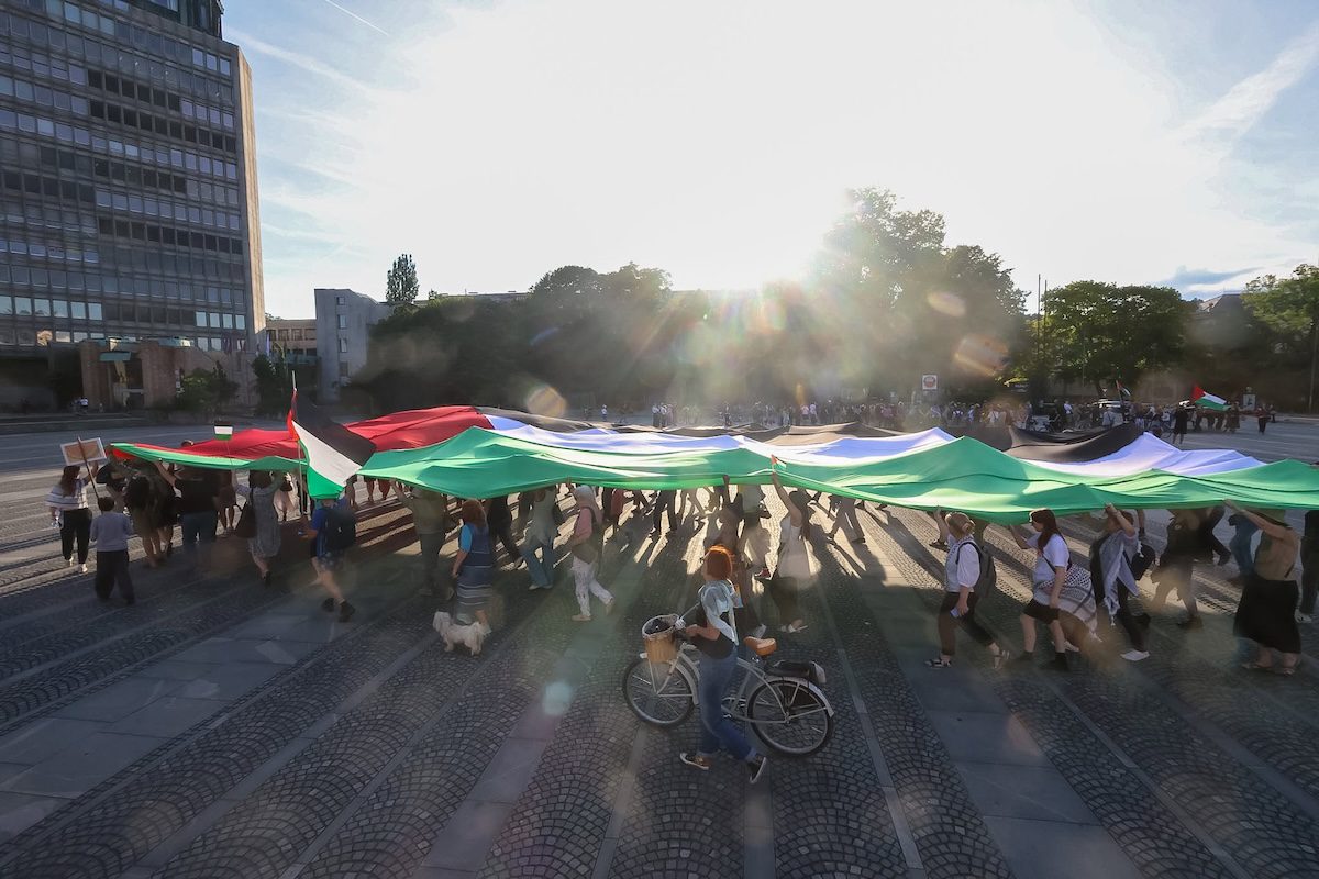 People march and hold a massive Palestine flag