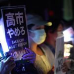 Japanese woman holds sign demanding the resignation of the prime minister.