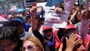 VZ US sanctions - BT News Woman holds sign that reads Down with the Sanctions! in Spanish